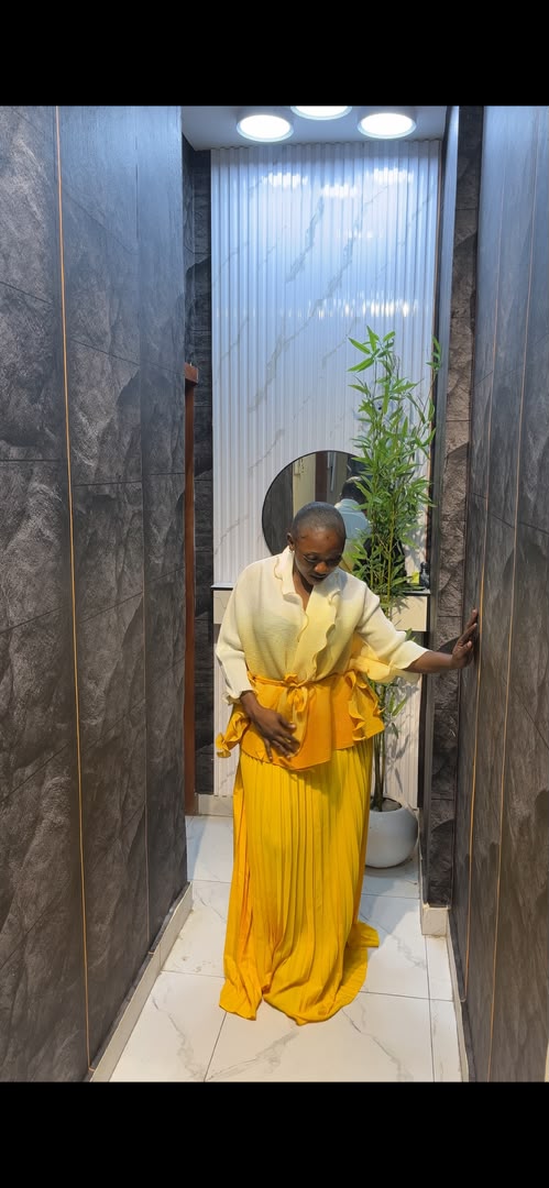 Woman wearing cream oversized blouse with golden yellow pleated maxi skirt and ruffled waist detail