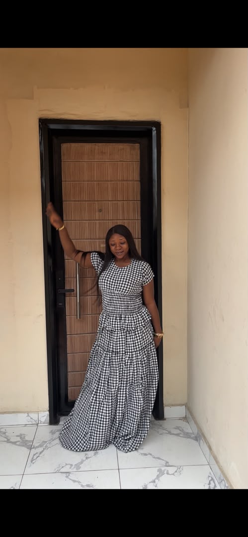Woman wearing black and white gingham check tiered maxi dress with fitted bodice and full flowing skirt